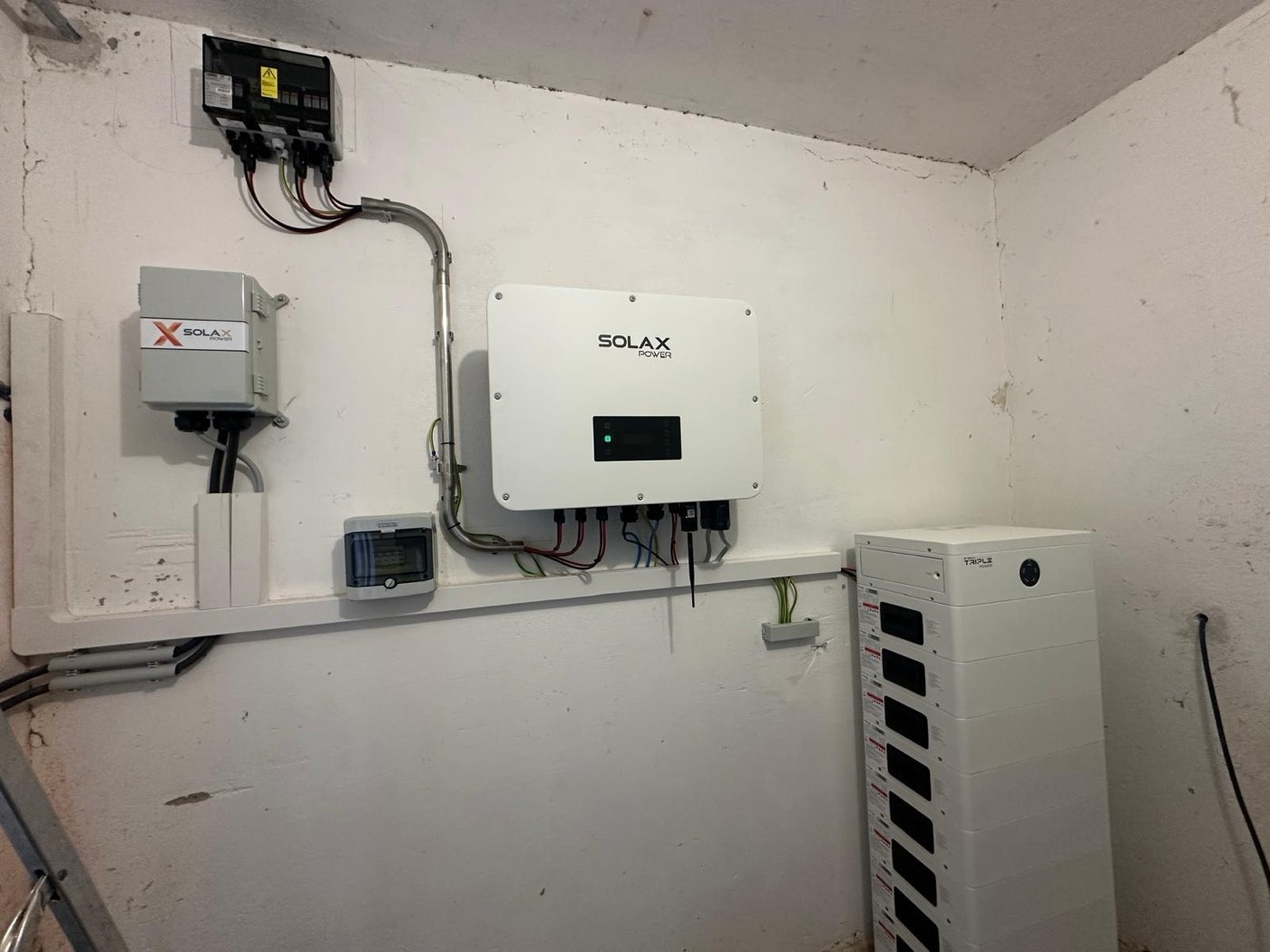 Technikraum mit SolaX Hybrid-Wechselrichter, Triple-Power-Speicherturm und Schutztechnik an der Wand