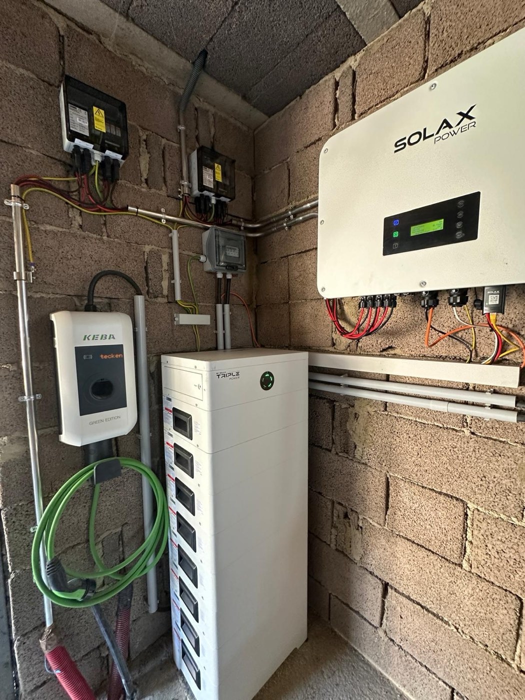 KEBA-Wallbox mit grünem Ladekabel neben einem SolaX Triple-Power-Speicherturm und Hybrid-Wechselrichter